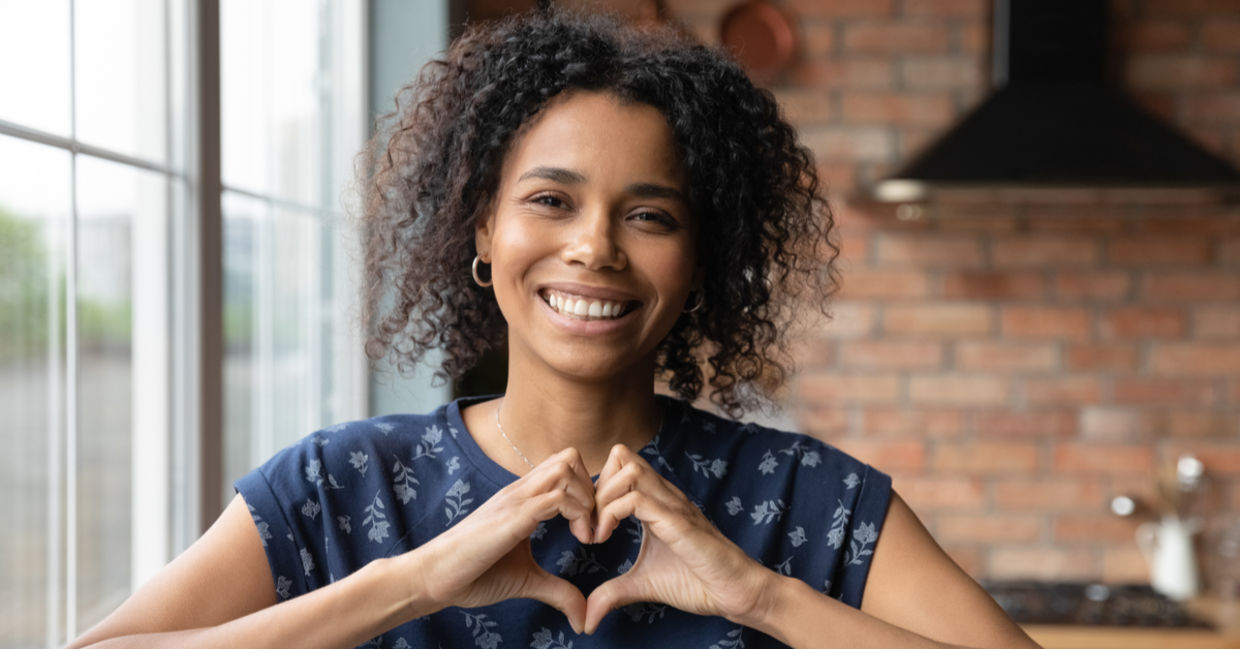 Portrait of kind student showing heart symbol with her hands