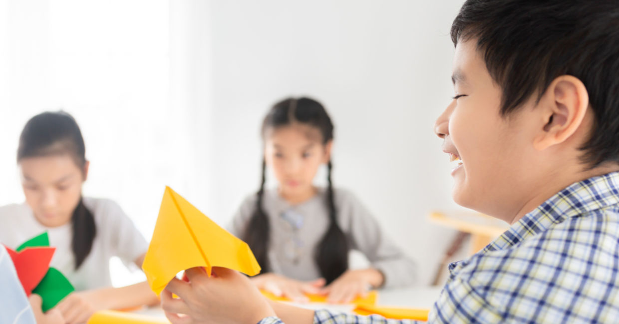 Children developing confidence and creativity by doing origami at school.