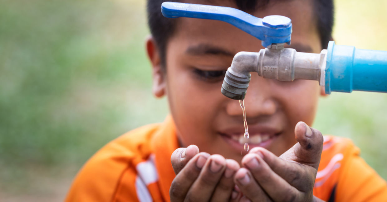 Boy drinking from an outdoor tap