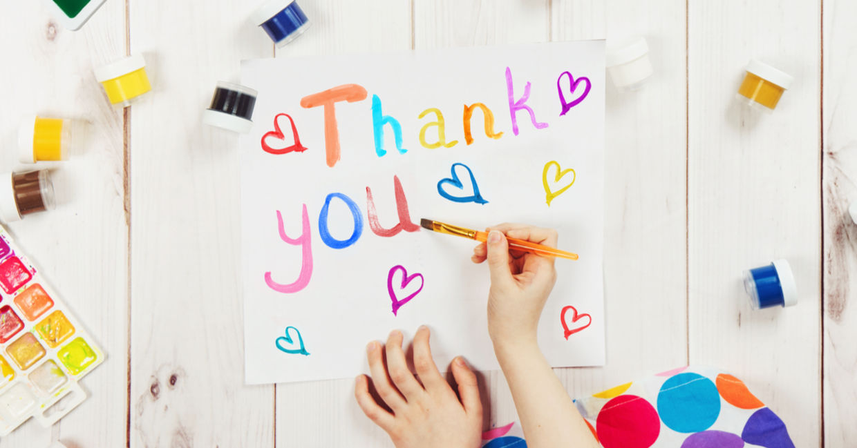 A young child is making a thank you card.