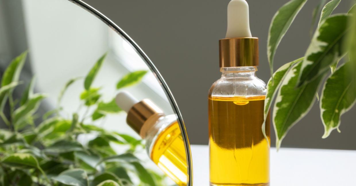 A bottle of vitamin E oil, nourishing for skin and hair, is beside a makeup mirror.