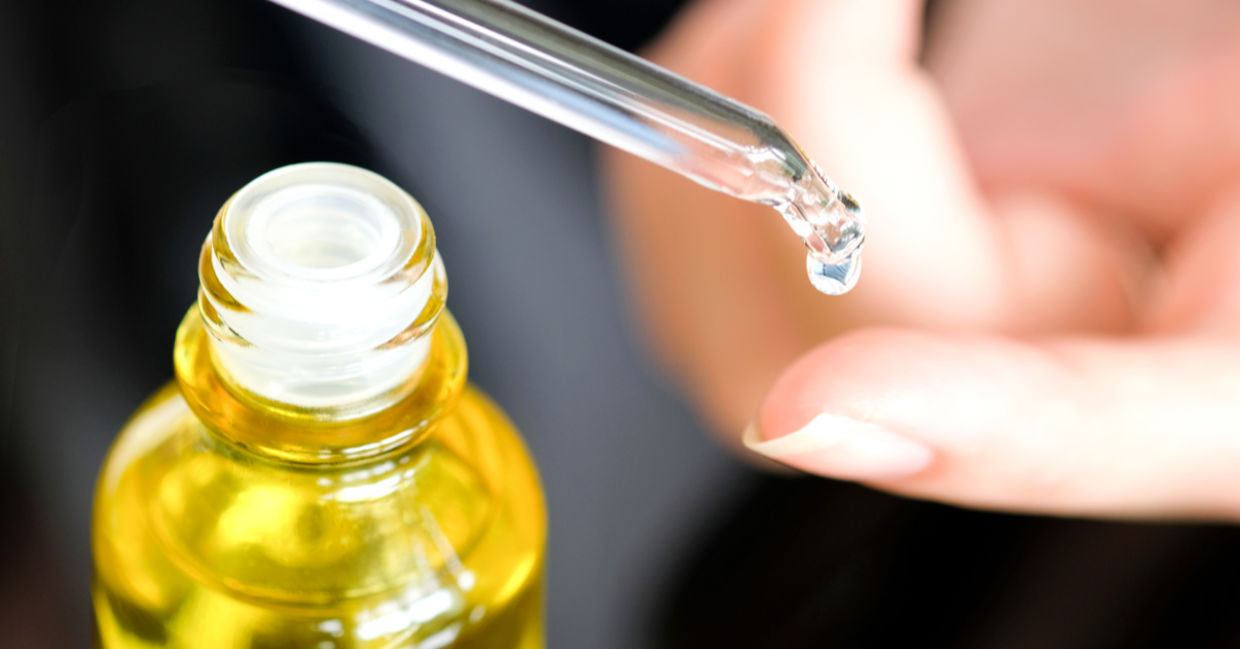 A woman places a drop of healing vitamin E oil on her skin.