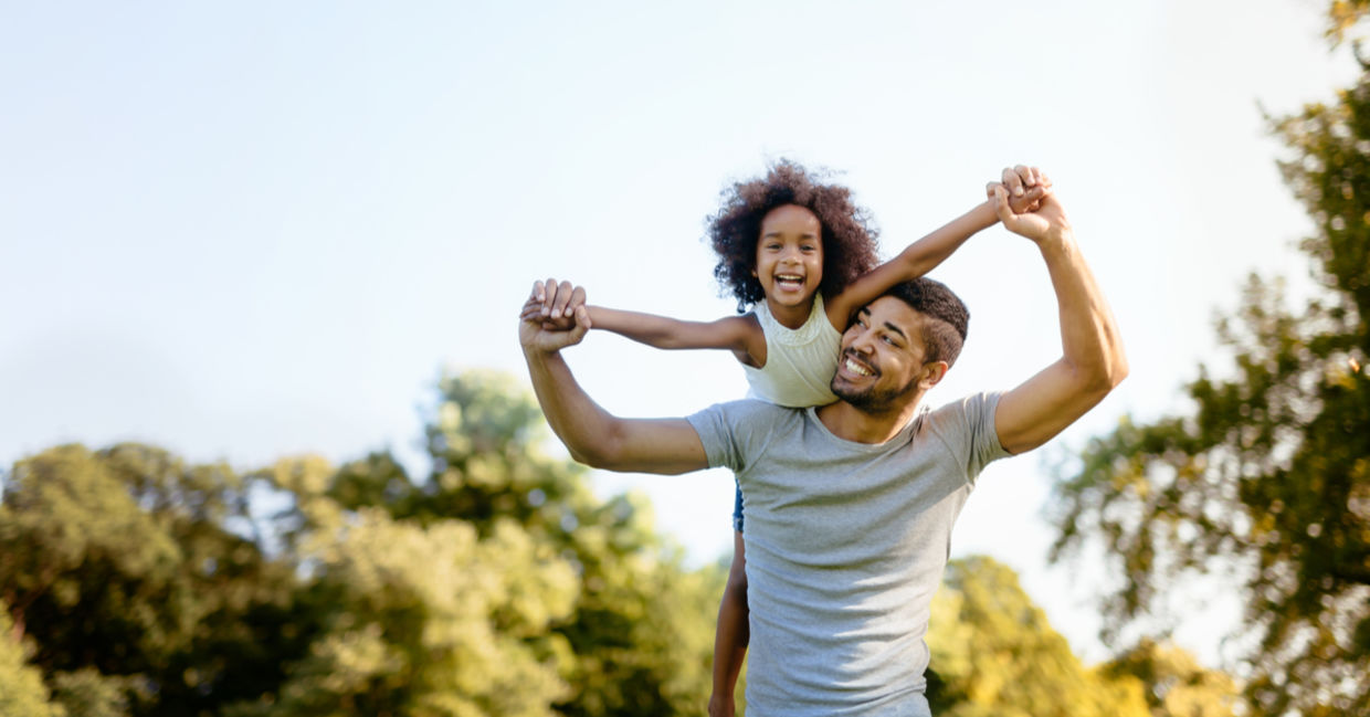 Father carrying daughter on his back outdoors