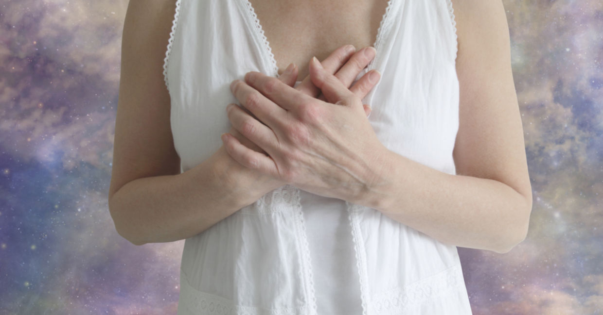 An emotional empath holds her hands to her heart, feeling the emotions of those around her.