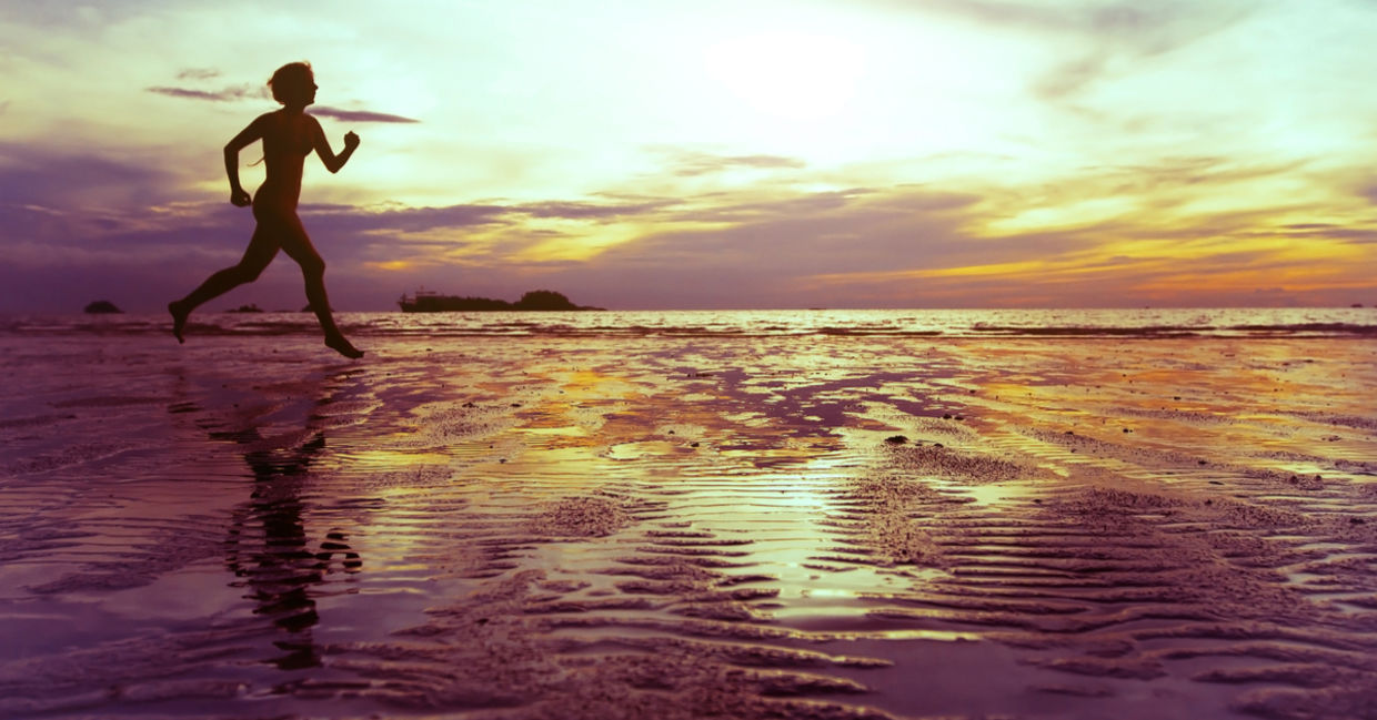 Healthy and mindful woman running on the beach.