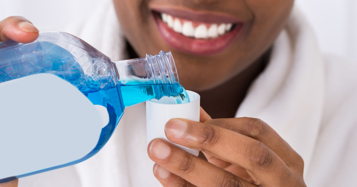 A woman using a DIY tea tree oil mouthwash.