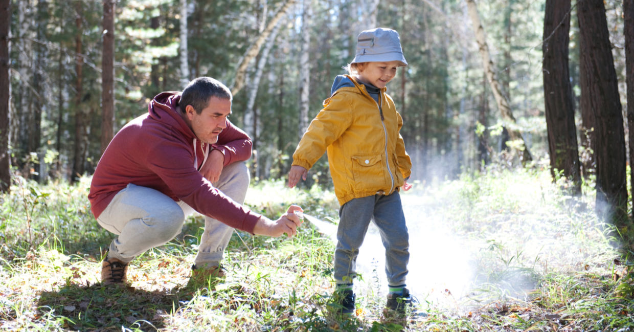 Dad using natural insect repellent made from tea tree oil on his son