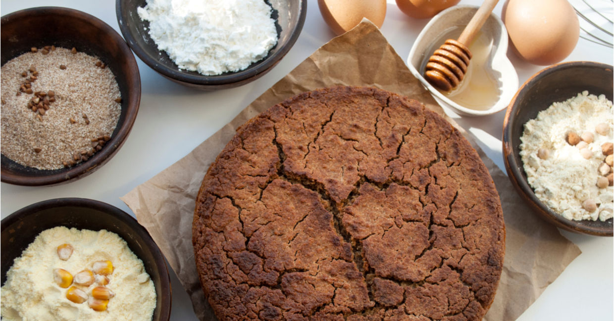 A selection of gluten-free flours beside a healthy freshly baked muffin.