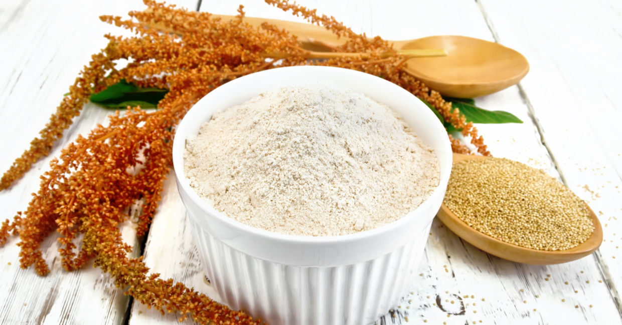 Whole amaranth seeds and ground gluten-free amaranth flour beside a sprig of amaranth.