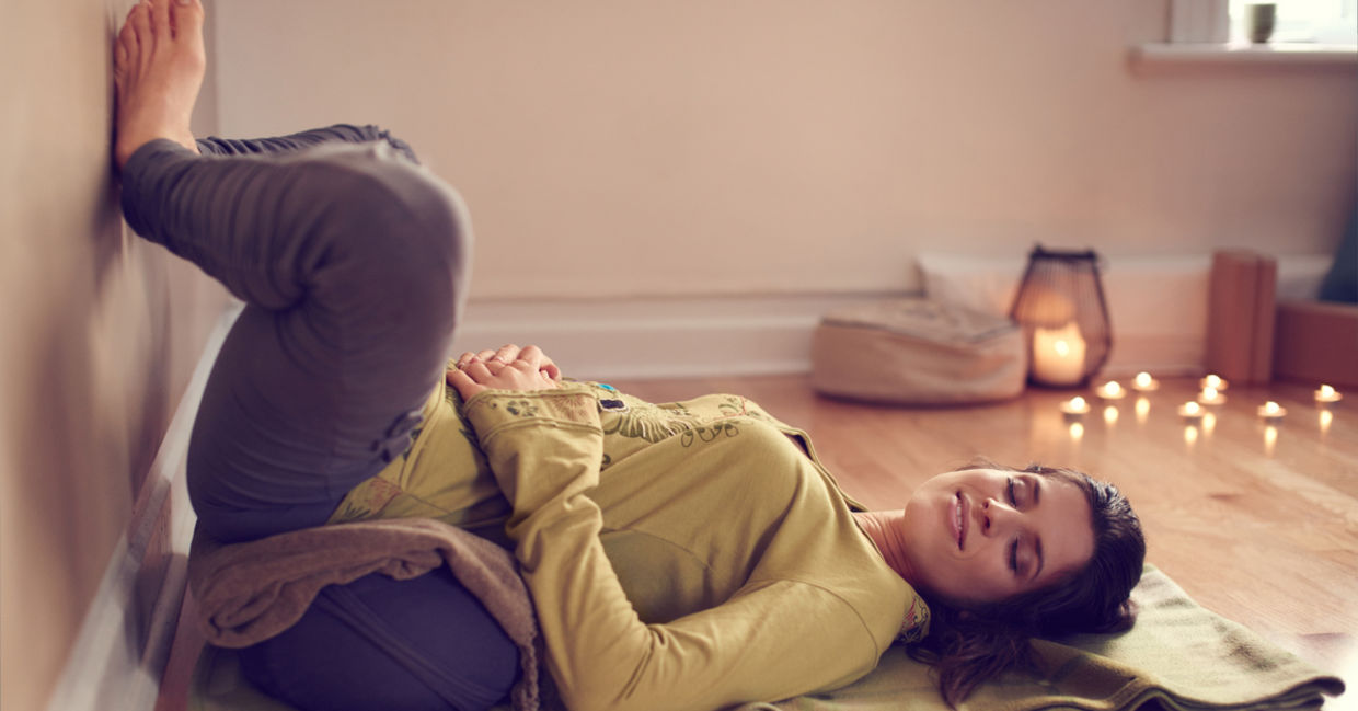 A woman does yoga in her meditation corner, surrounded by lit candles.