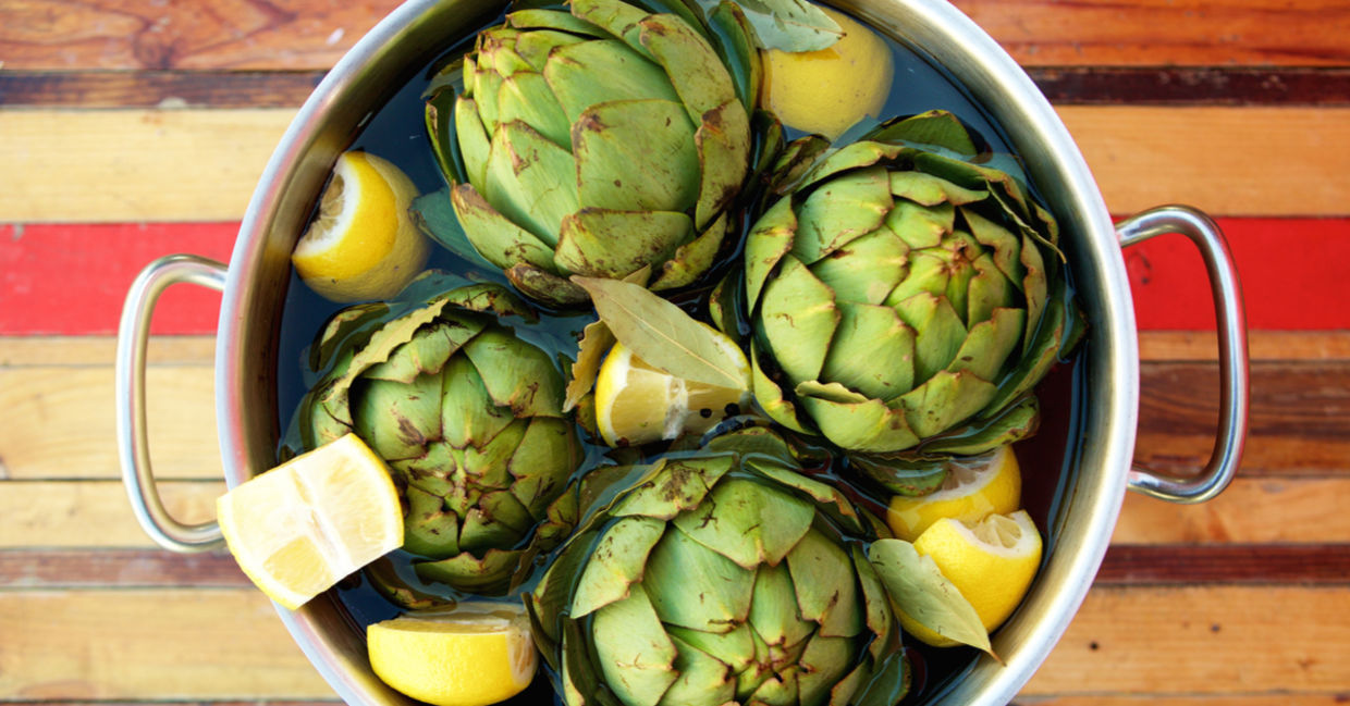 Fresh artichokes and lemons in a pot.