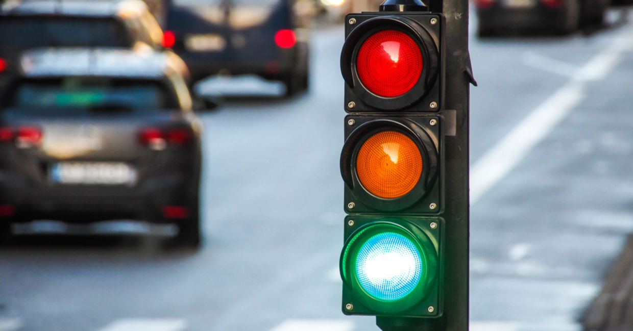 A traffic light, pedestrian crossing, and cars at a busy intersection.