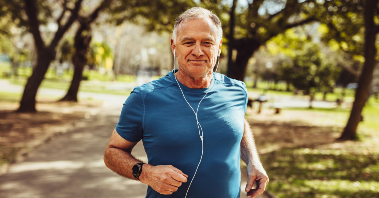 A man smiles as he jogs in a park.