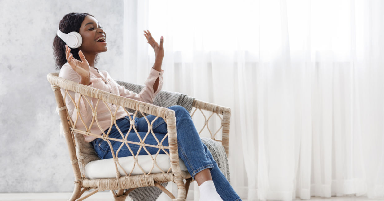 A woman sits in a chair enjoying listening to music.
