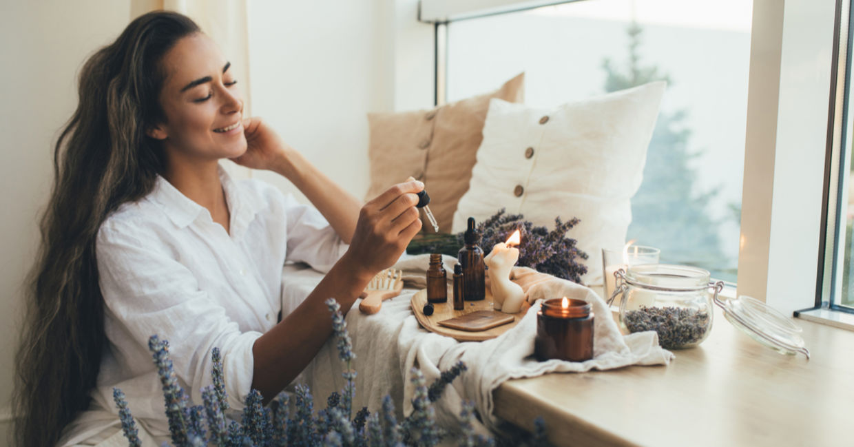 Woman applying essential lavender oil to her hair as part of her beauty ritual.