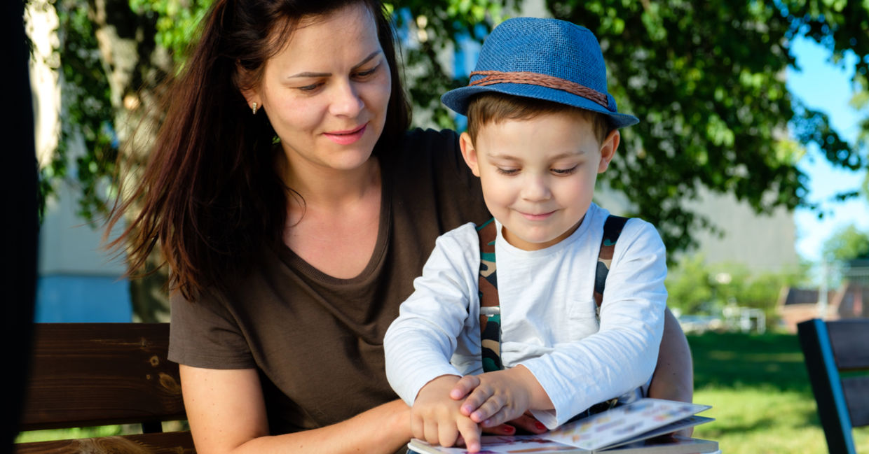 Happy mother listening to her son as he reads his book out loud.