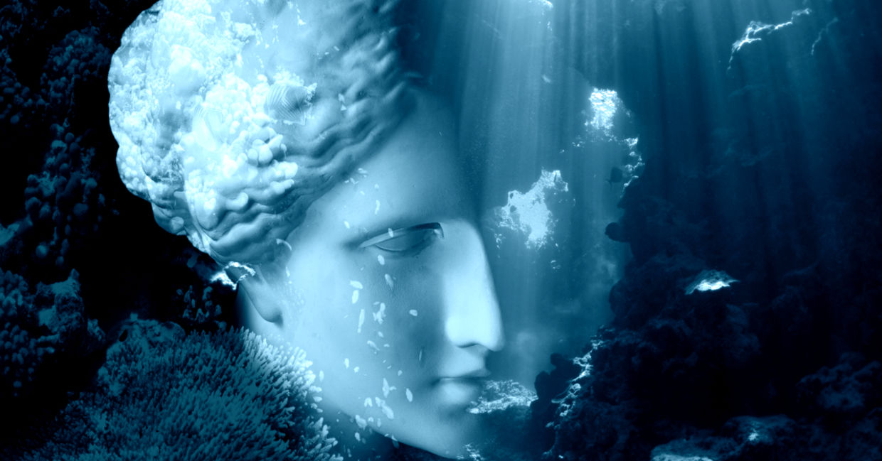 Face of ancient status on an underwater background with corals and fish.