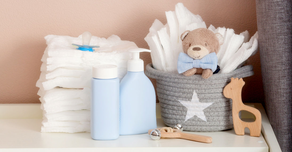 A stack of diapers, toys and baby accessories on a changing table.