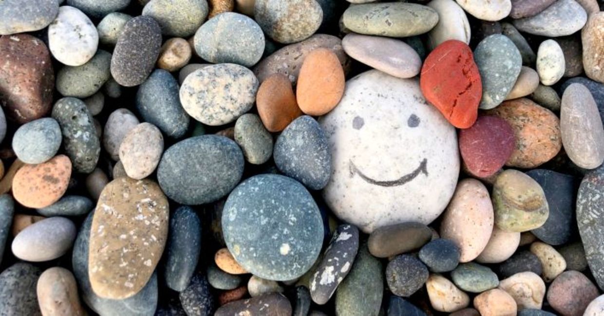 Stone with a painted smile to illustrate kindness.