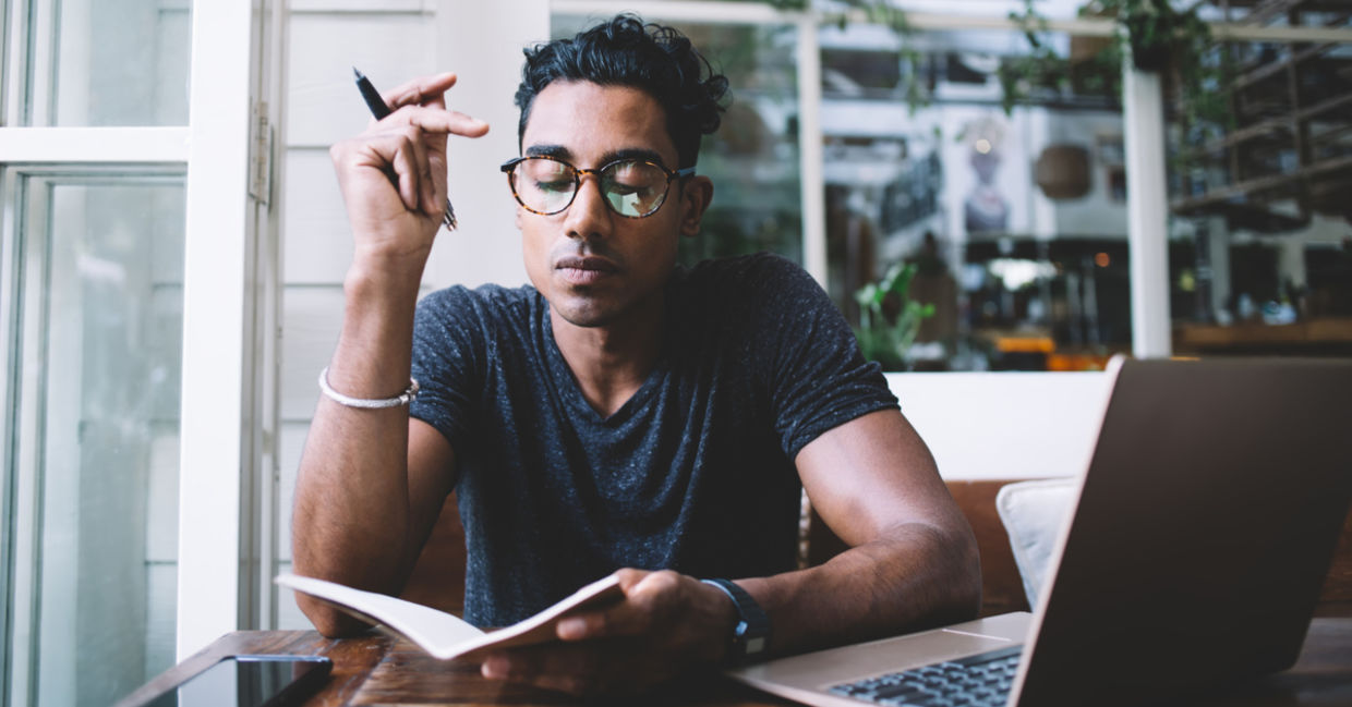 Concentrated man thinking and taking notes in a cafe.