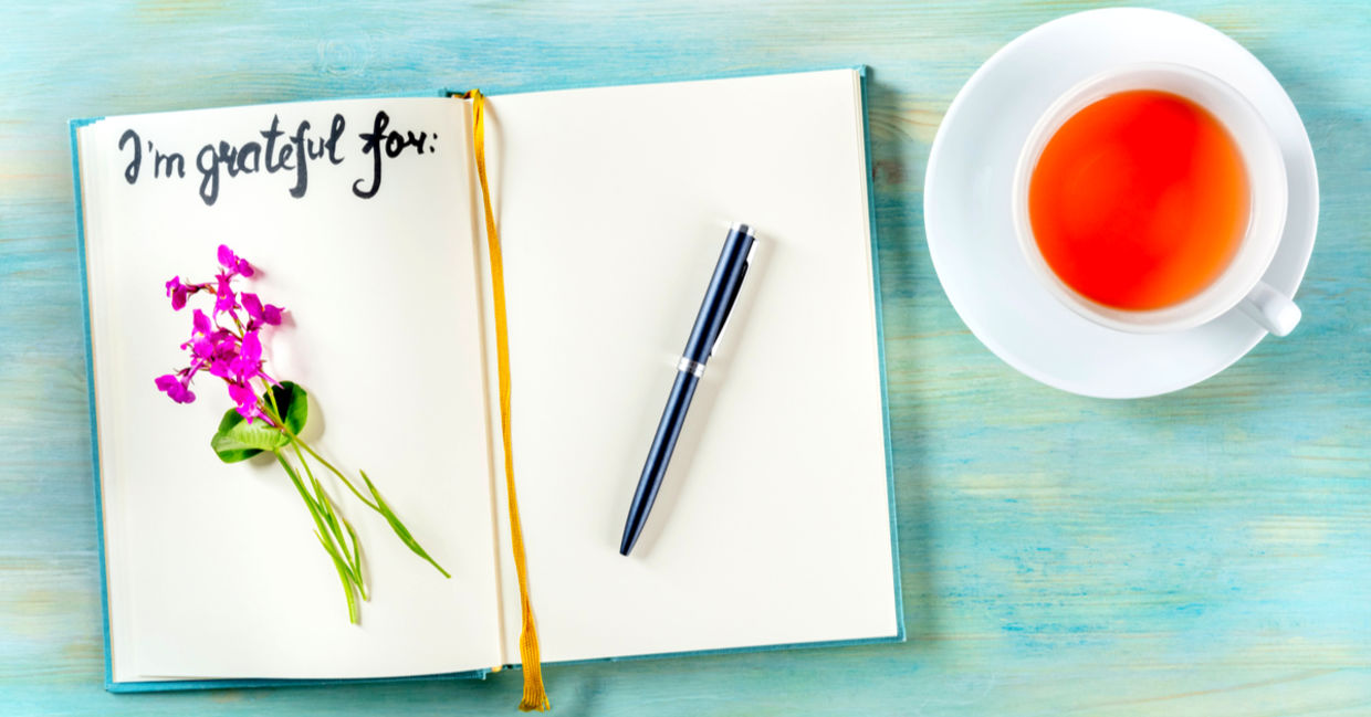Gratitude journal with a pen and a cup of tea.