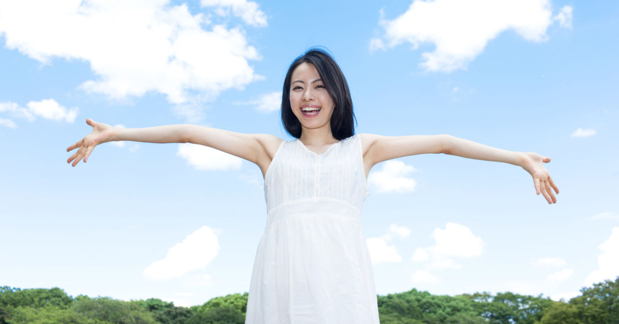 A woman happily embraces a sunny summer’s day.
