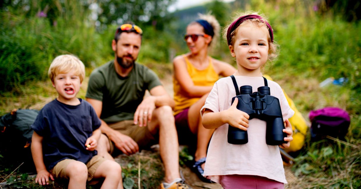 Family with small children hiking outdoors in summer.