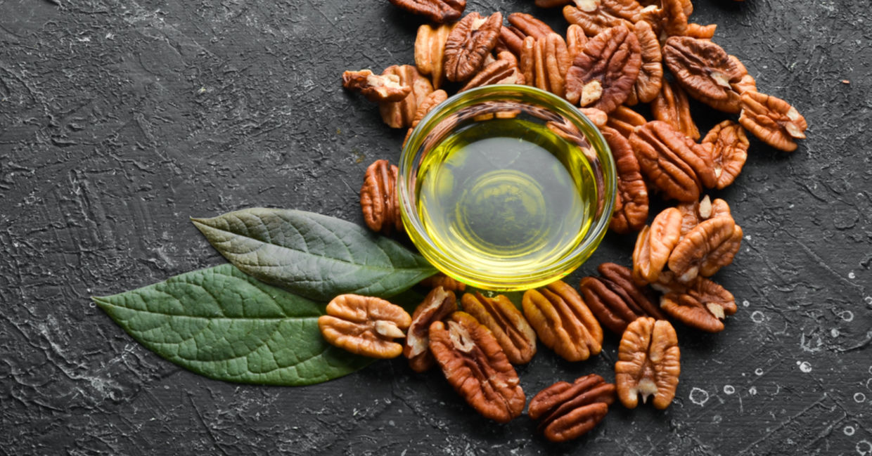 Fresh, raw pecans and a bottle of pecan oil.