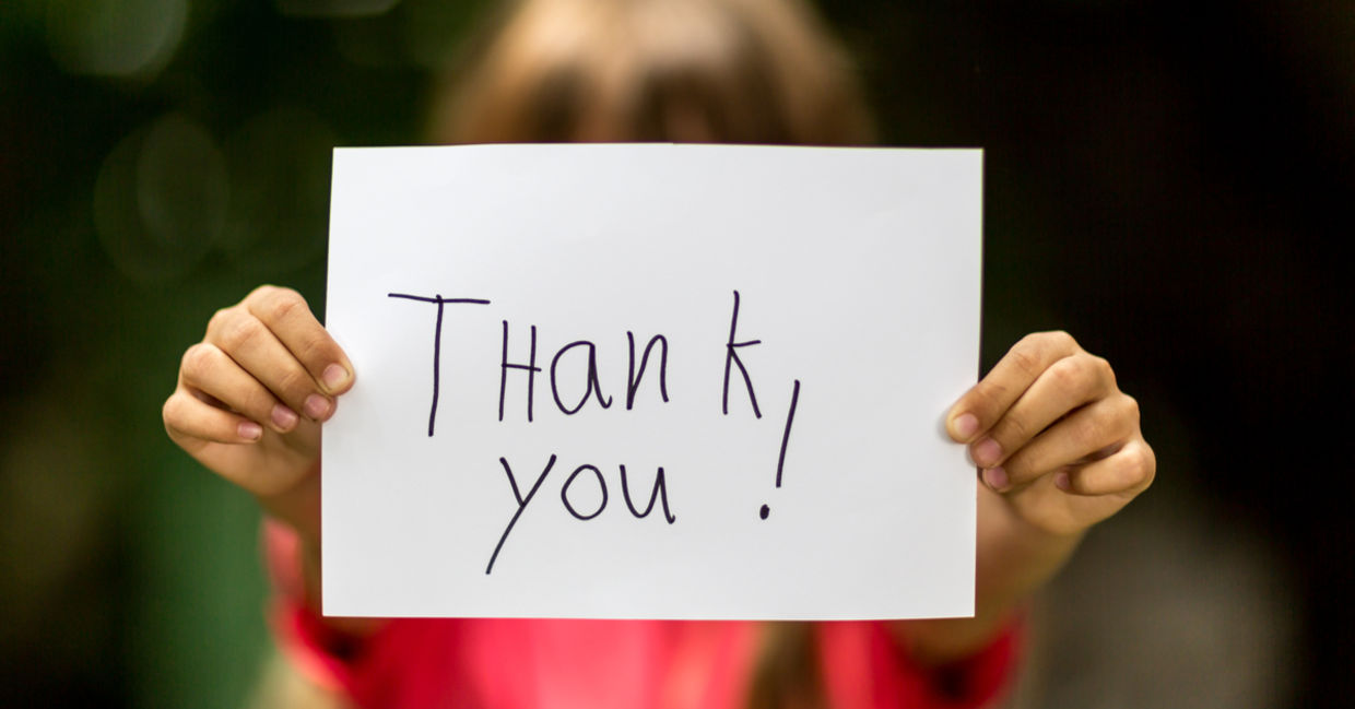 A girl holding a sign with the words Thank You.