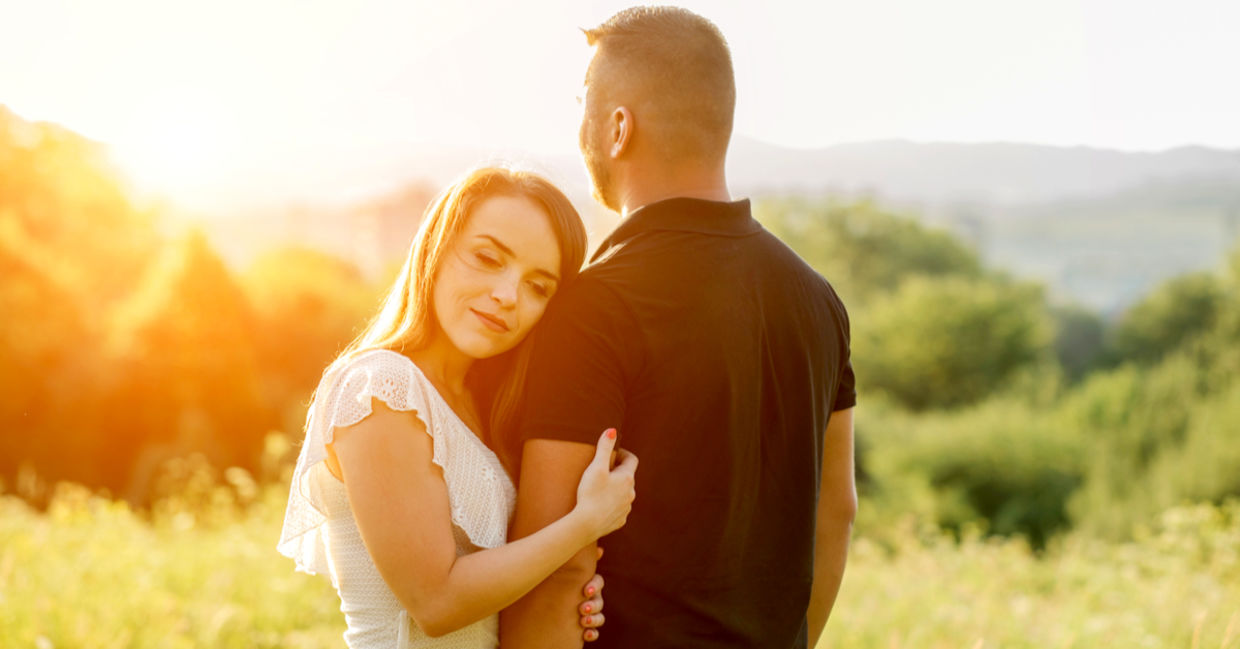 Couple hugging in the park at sunset.