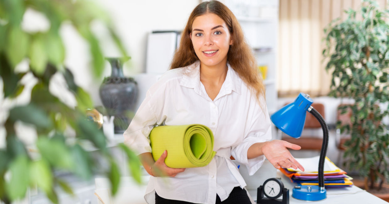 Happy young office worker with yoga mat.