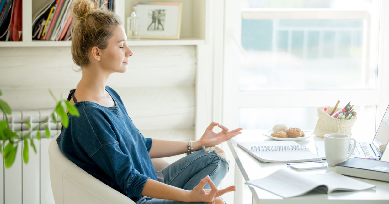 Woman doing yoga at her home office desk.