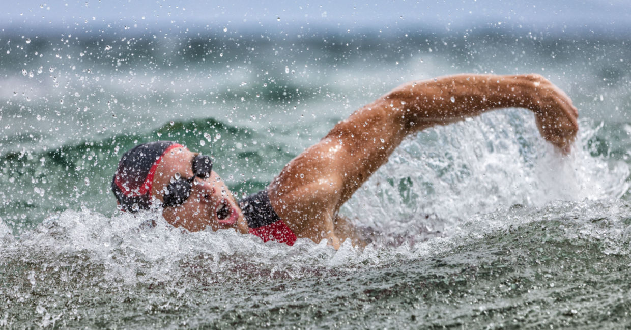 Swimmer in ocean waves wearing a swim cap.