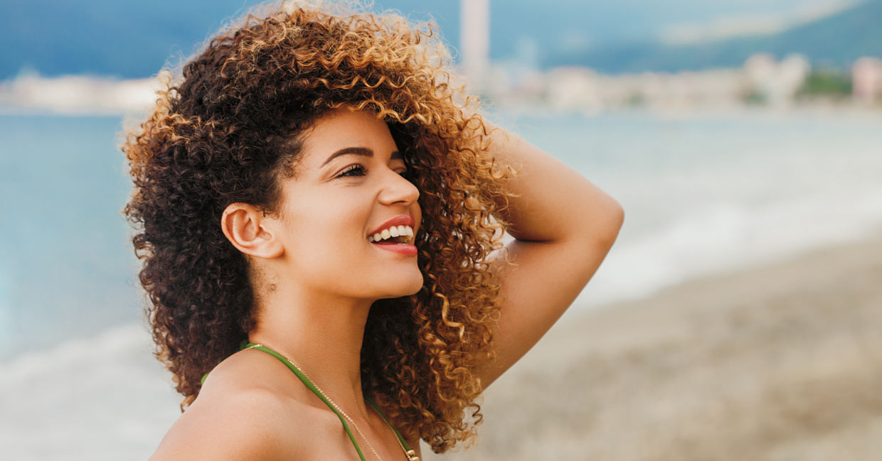 Woman with curly hair enjoying the beach.