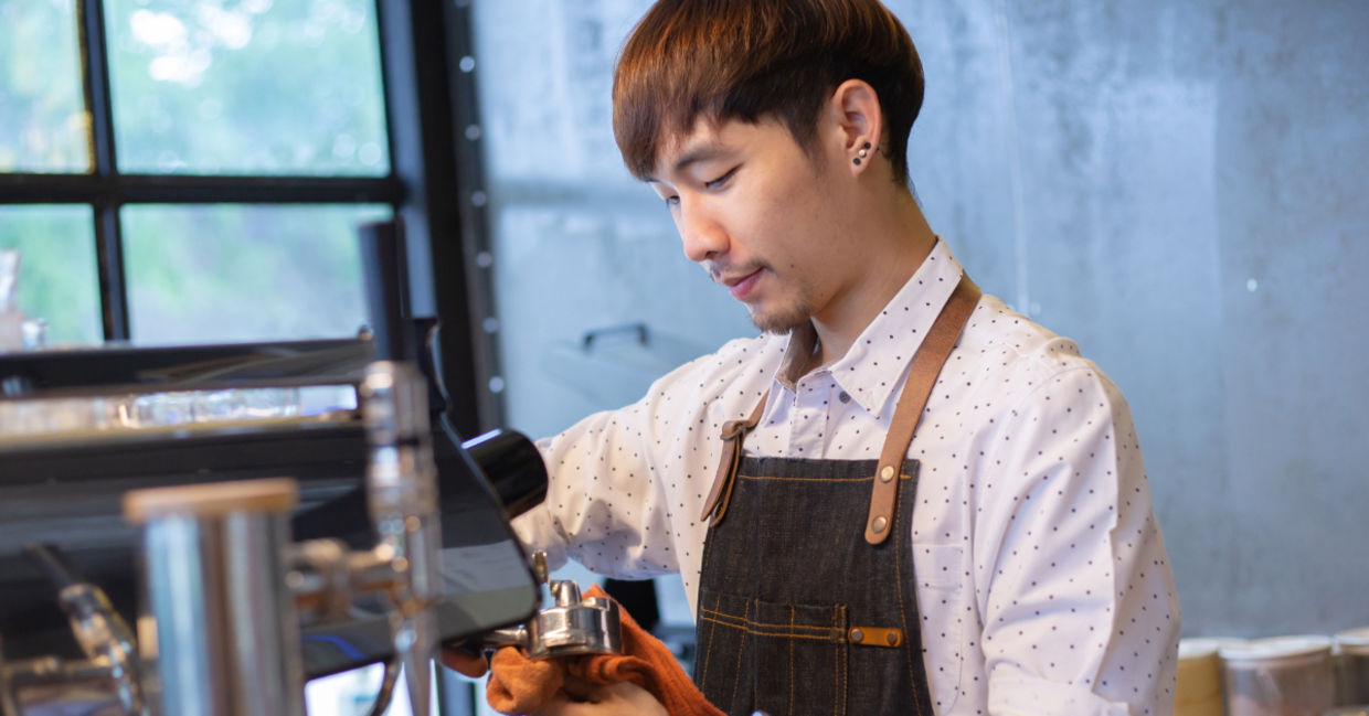 Barista at work cleaning equipment in a café.