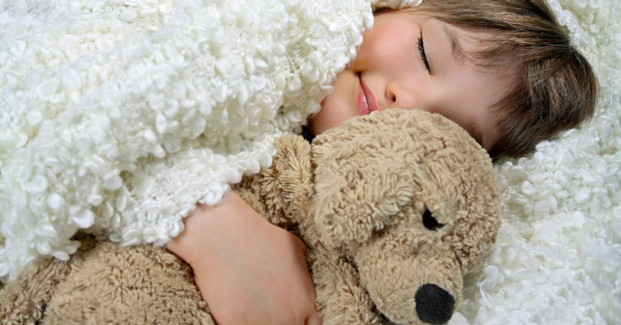 Smiling girl holding a precious soft toy.