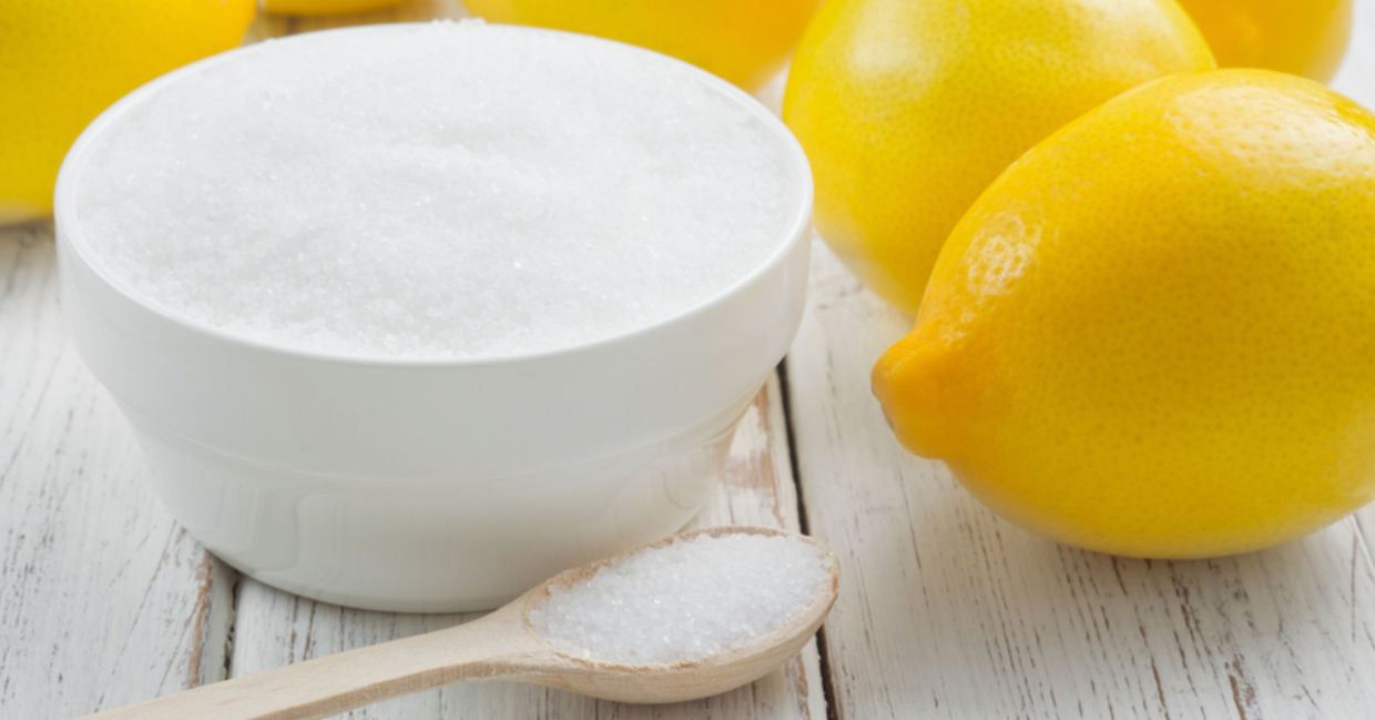 A bowl of citric acid beside lemons.