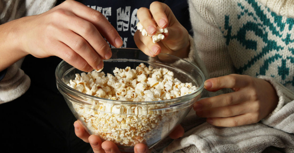 Watching a movie while enjoying popcorn.
