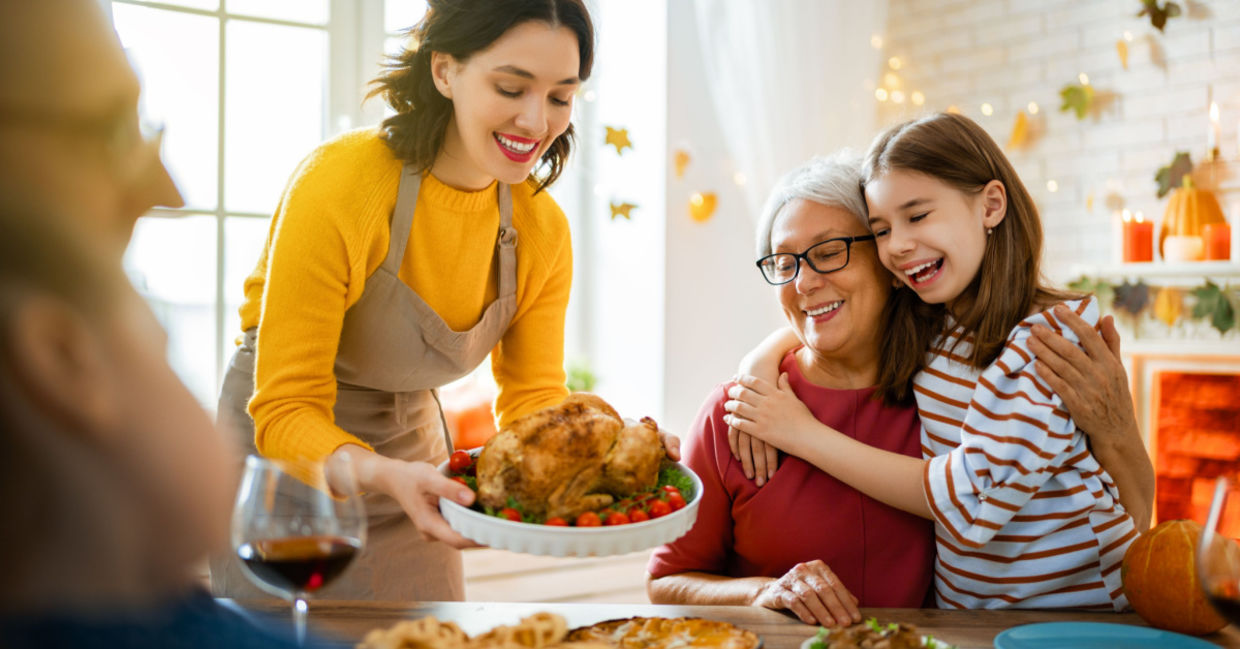 A family is seated around the table for a traditional Thanksgiving dinner.