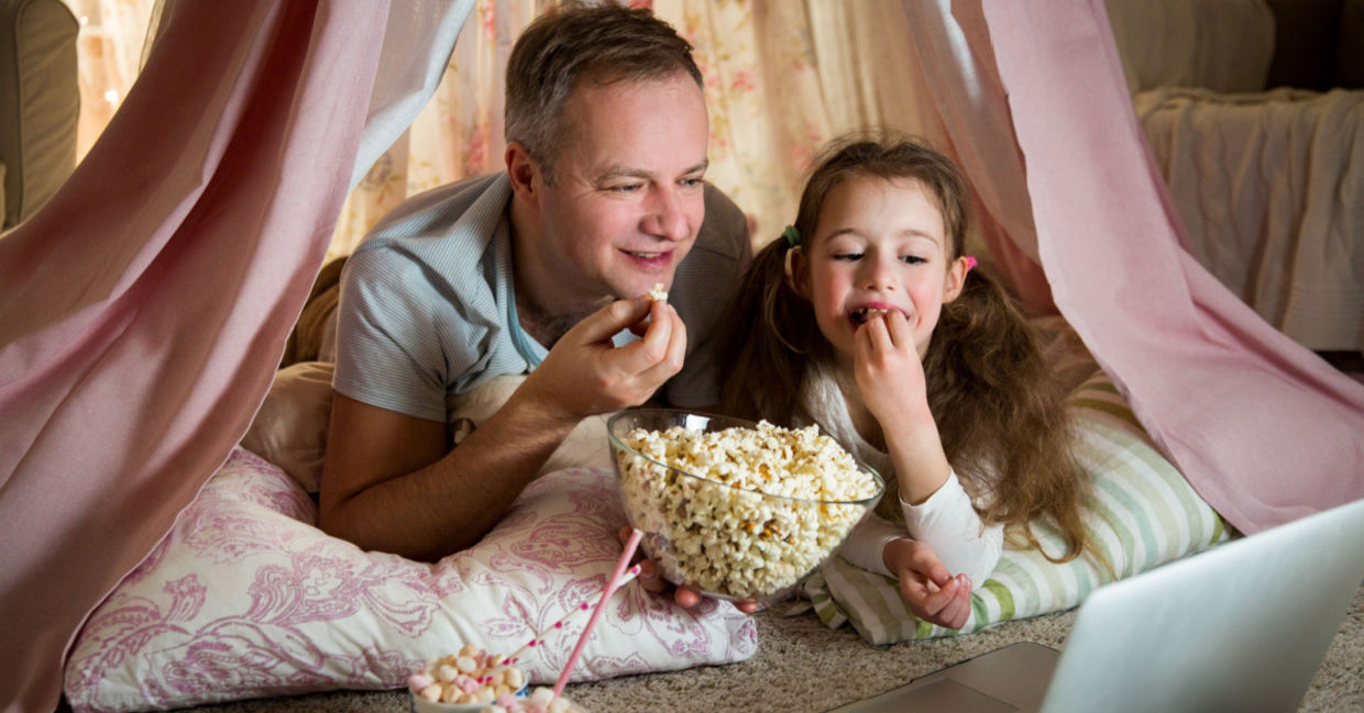 Father and daughter enjoying a dog-themed movie together.
