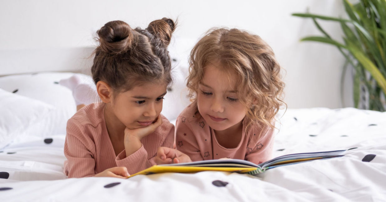 Two sisters reading a book before bedtime.