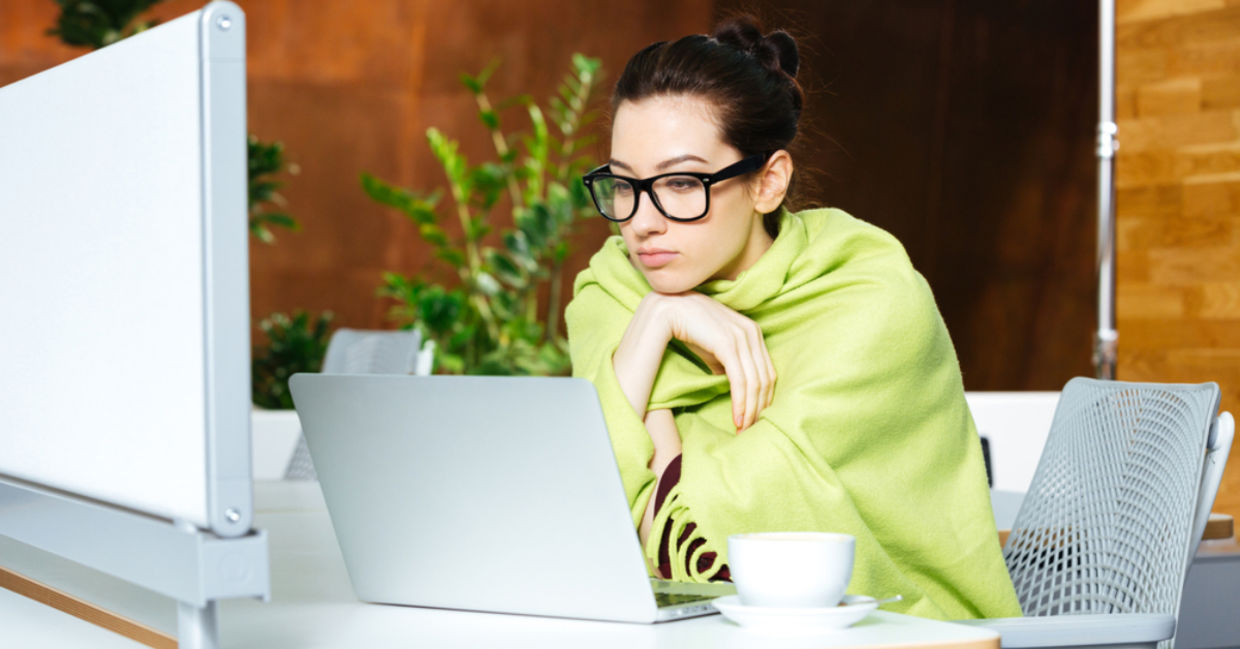 Woman wrapped in a shawl due to feeling cold in her workspace.