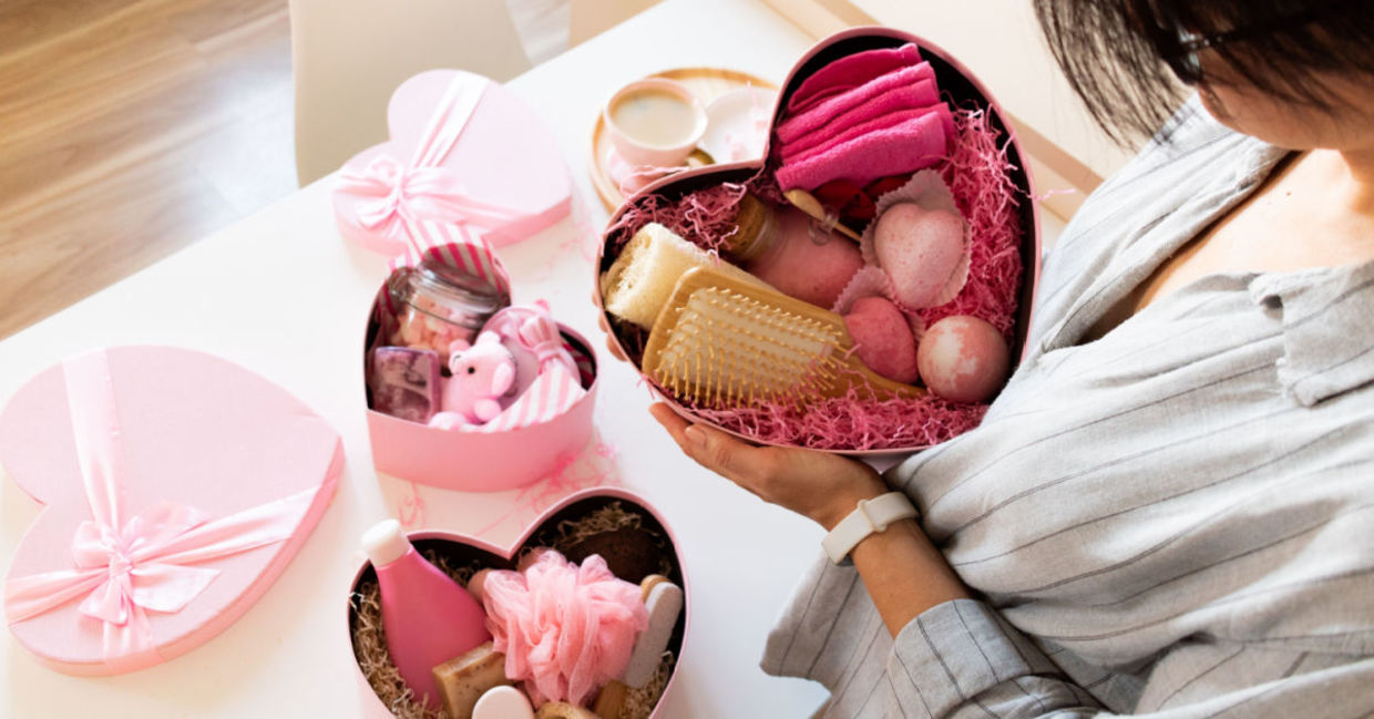 A woman holds a gift of luxurious home spa items.