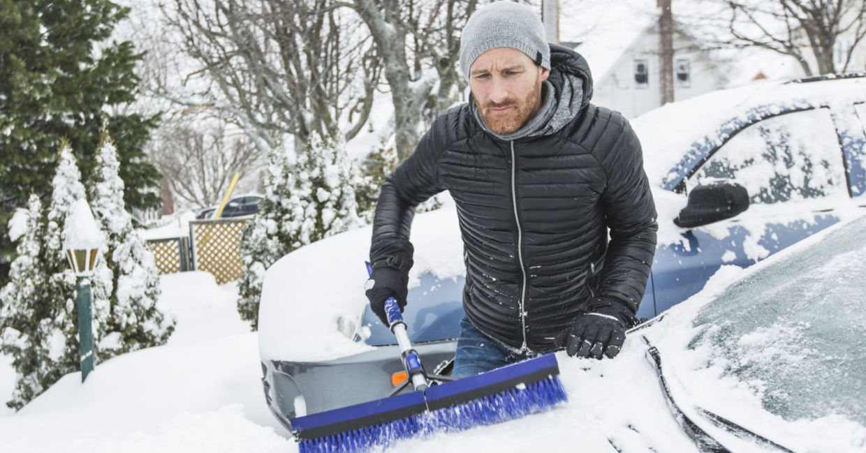 Man cleaning off neighbor's snowbound car,