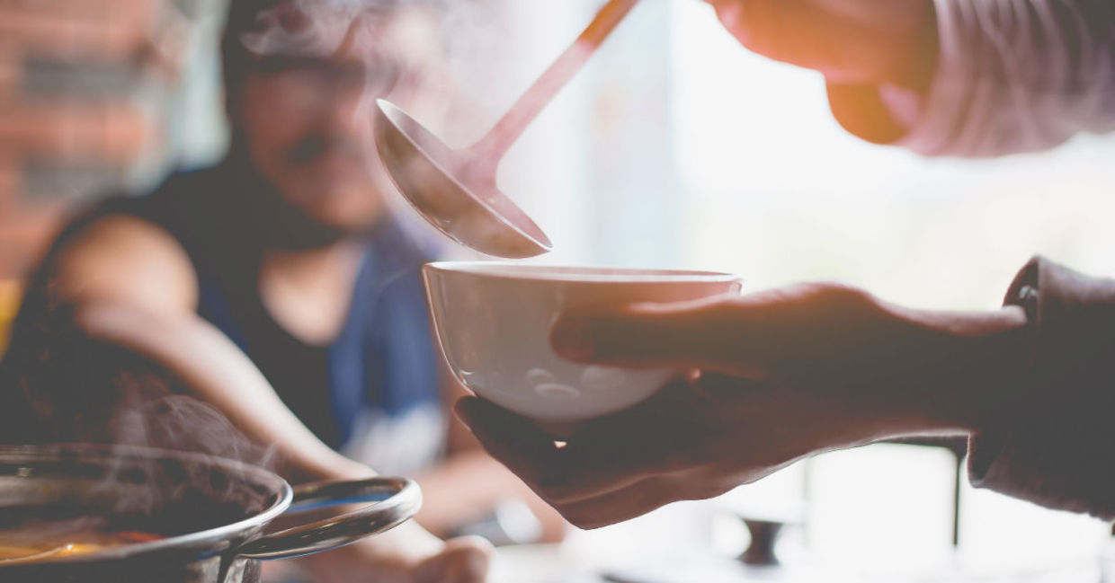 A woman warms up with a hearty soup.