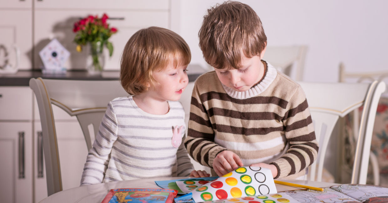 Two kids playing with stickers.
