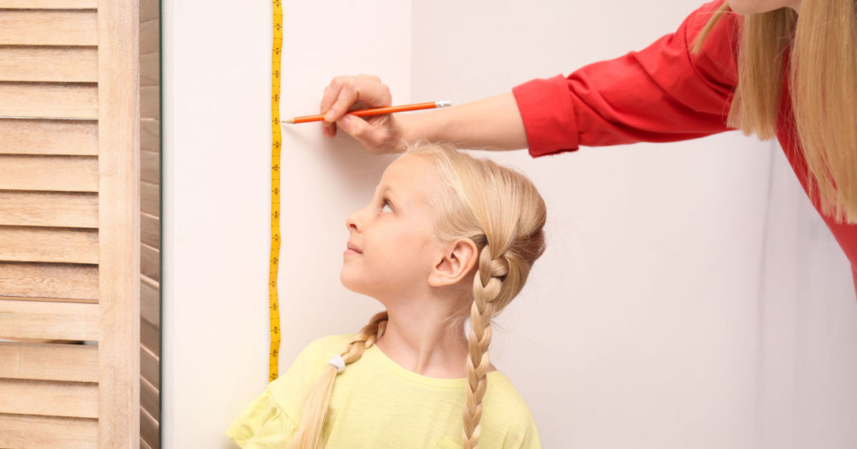 Mother measuring how much her daughter grew.