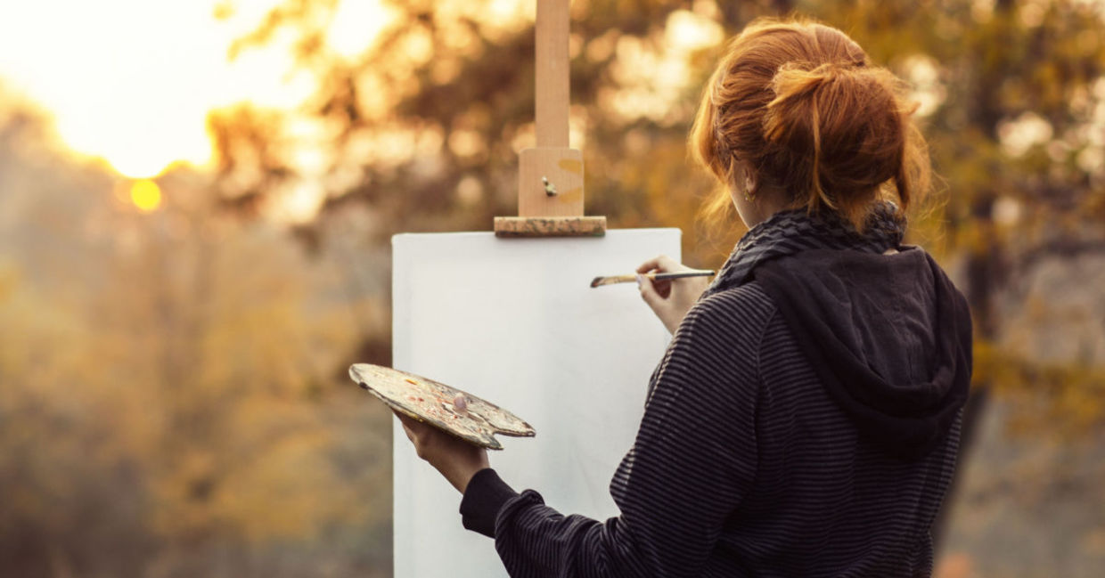 A woman enjoying her painting hobby and taking in the beautiful landscape