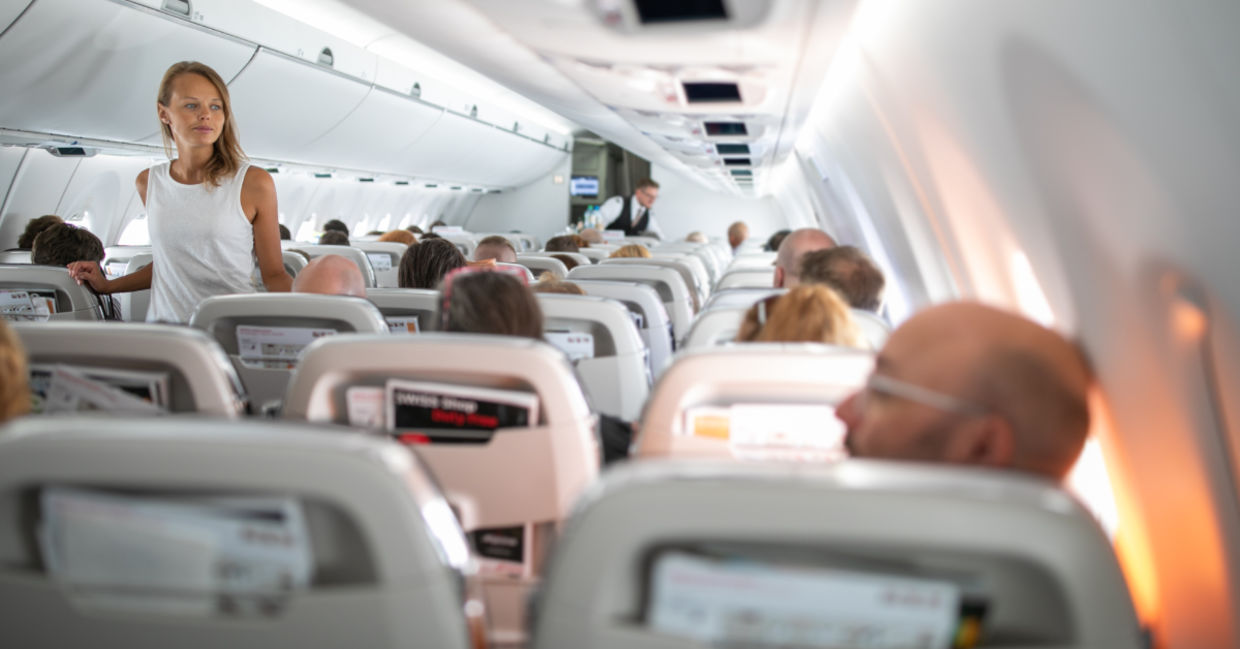 Young woman aboard an airplane walking in the aisle