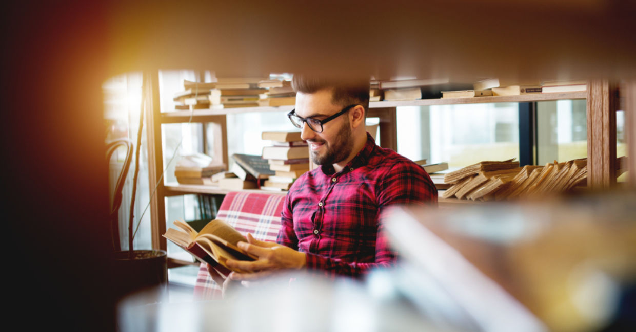 Young man reading a book at a modern library.